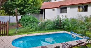 ein Swimmingpool in einem Hof mit einem Haus in der Unterkunft Cabañas La Petunia in Santa Rosa de Calamuchita