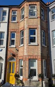 a brick building with a yellow door on a street at Bournemouth Beach Boutique with Hot Tub in Bournemouth