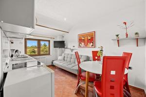 a kitchen and living room with a table and red chairs at Apartments Fjord in Brajkovići