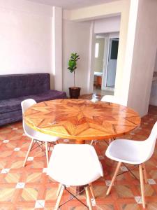 a living room with a wooden table and white chairs at Lindo departamento in Toluca