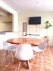 a dining room with a wooden table and white chairs at Lindo departamento in Toluca