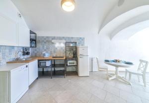 a kitchen with white appliances and a table with chairs at O'Vascio Sant'Angelo in Serrara Fontana
