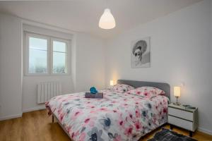 a bedroom with a bed with a floral bedspread at Le Belvédère du Lac Blanc in Orbey