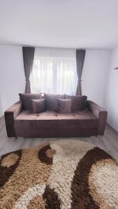 een bruine bank in een woonkamer met een groot raam bij Casa Bianchi Vatra Dornei in Vatra Dornei