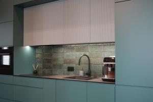 eine Küche mit weißen Schränken und einer Spüle und einer Mikrowelle in der Unterkunft Smoleńsk 33 Luxury Apartment in Krakau