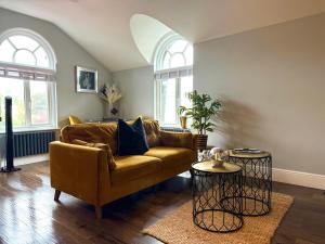 a living room with a brown couch and two windows at 3 West End Boutique Apartment in Bowness-on-Windermere