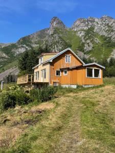 a house on a hill with a mountain in the background at Skokkelvika gård in Vestvågøya