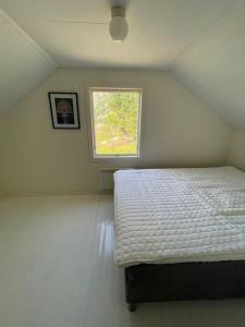 a bedroom with a bed in a room with a window at Skokkelvika gård in Vestvågøya