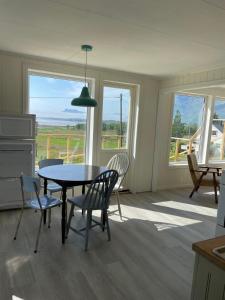 a dining room with a table and chairs and windows at Skokkelvika gård in Vestvågøya