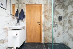 La salle de bains est pourvue d'une douche et d'une porte en bois. dans l'établissement COY Apartments Purkersdorf - Garden Comfort for Work Family near Vienna, à Purkersdorf 170 autres photos