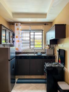 a kitchen with black cabinets and a sink and a window at Oasis Villas- Naalya in Kampala