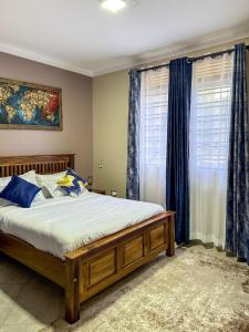 a bedroom with a large bed with blue curtains at Oasis Villas- Naalya in Kampala
