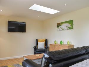 a living room with a couch and a tv on the wall at Sherwood Forest Lodge 2 in Clipstone