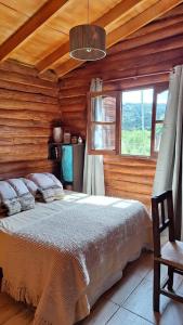 Un dormitorio con una cama en una cabaña de troncos en Cabaña La Vista, en La Caldera