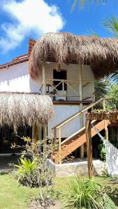 a house with a thatch roof and a porch at Pousada Tatuamar Café & Bistrô - 150 m da praia in Pôrto de Pedras
