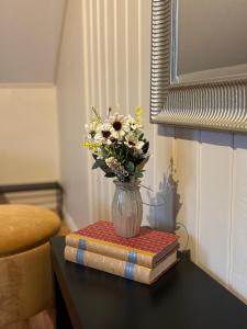 een vaas met bloemen op een tafel met boeken bij Komfort og stil-perfekt for ferie og jobb in Gjøvik +8 foto's