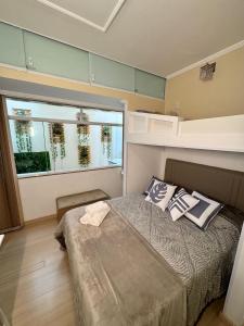 ein Schlafzimmer mit einem Bett und einem großen Fenster in der Unterkunft Estúdio no Centro Reformado e Decorado in Nova Friburgo