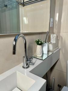 a bathroom counter with a sink and a mirror at Estúdio no Centro Reformado e Decorado in Nova Friburgo