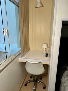 a desk with a chair in a room with a window at Estúdio no Centro Reformado e Decorado in Nova Friburgo