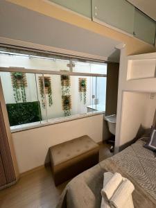 a bedroom with a large window with a view of a bathroom at Estúdio no Centro Reformado e Decorado in Nova Friburgo +17 photos