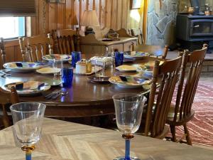 a wooden table with plates and glasses on it at Midtown Meadow Cabin in Ruidoso