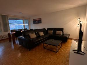 a living room with a black leather couch and a table at Swiss Suites Oberrohrdorf in Rohrdorf