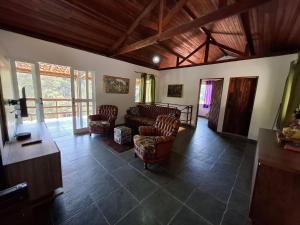 Sítio com 07 dormitórios, piscina e jogos LT0042 في Bairro dos Soares: غرفة معيشة مع كراسي وأريكة ونوافذ