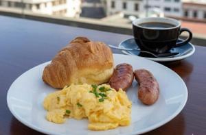 a plate of eggs and sausage and a cup of coffee at HOTEL COMFORT INN Torre B in Quito +39 photos