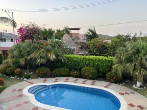 a swimming pool in a yard with trees and flowers at Villa Las Marias in Santa Verónica