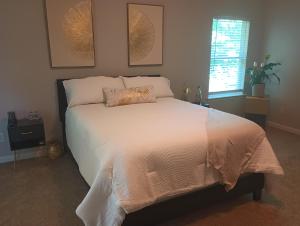 a bedroom with a bed with white sheets and a window at The Serene in Between in Snellville