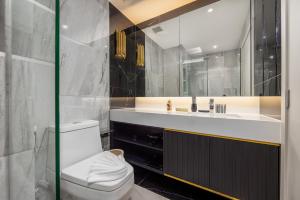 a bathroom with a white toilet and a sink at Bellevue Lagoon Premium Apart Hotel by TropicLook in Laguna Phuket