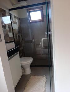 a bathroom with a toilet and a glass shower door at Casa Xandó in Porto Seguro +6 photos