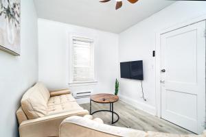 a white living room with a couch and a table at Bright Quiet One Bedroom Apartment in Windsor