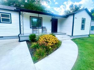una casa con dos sillas y flores delante de ella en The McKinney dentrally located a few blocks from Emma St and Downtown four bedrooms, en Springdale