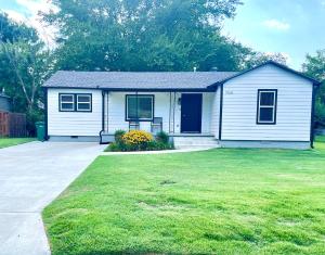 una pequeña casa blanca con un patio de césped en The McKinney dentrally located a few blocks from Emma St and Downtown four bedrooms, en Springdale