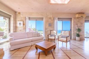 ein Wohnzimmer mit Sofa, Stühlen und Fenstern in der Unterkunft Thomais 2-Villa Stone Estate with Pool & Sea Views in Agia Pelagia + 52 Fotos