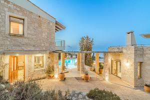 a stone house with a courtyard and a swimming pool at Elegant 2-Villa Stone Estate with Pool & Sea Views in Agia Pelagia