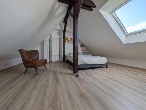 a bedroom with a bed and a chair in a attic at Traumwohnung über den Dächern Rüttenscheids in Essen +2 photos