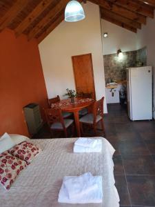 a bedroom with a bed and a table and a kitchen at Cabaña La Chiquita in Villa Giardino