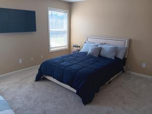 a bedroom with a bed with a blue comforter and a window at The Vibe in Conyers