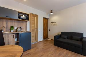 a living room with a black couch and a kitchen at Сучасна студія в центрі - Харківська набережна 3-8 in Kharkiv