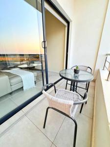 a table and chair on a balcony with a view of a bed at Elite Executive Suite Midrand in Midrand