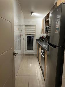 a small kitchen with a refrigerator and a tile floor at Departamento Centro Lagos in Temuco