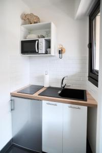 una cocina con fregadero y microondas en Beautiful modern fully furnished studio, en Levallois-Perret
