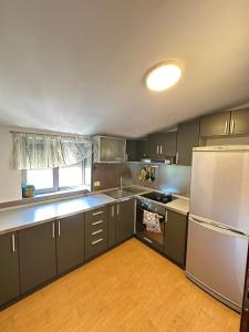 ティラナにあるHana Apartments TIRANAのキッチン(グレーのキャビネット、白い冷蔵庫付)