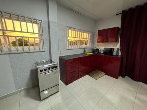 a kitchen with red cabinets and a stove at RJ Appartement in Paramaribo