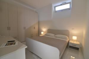 a white bedroom with a white bed and a window at Central Apartment in Matera +36 photos