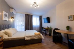 a bedroom with a bed and a table and a desk at Затишна студія біля метро Площа Конституції - Харківська набережна 3-10 in Kharkiv