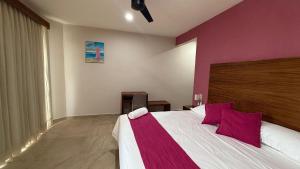 Bahías de HuatulcoAeropuerto Express Huatulco的一间带大床的卧室，墙壁是紫色的