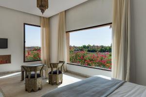 Un dormitorio con una cama y una vista de las flores. en Villa La Baraca, en Marrakech 51 fotos más